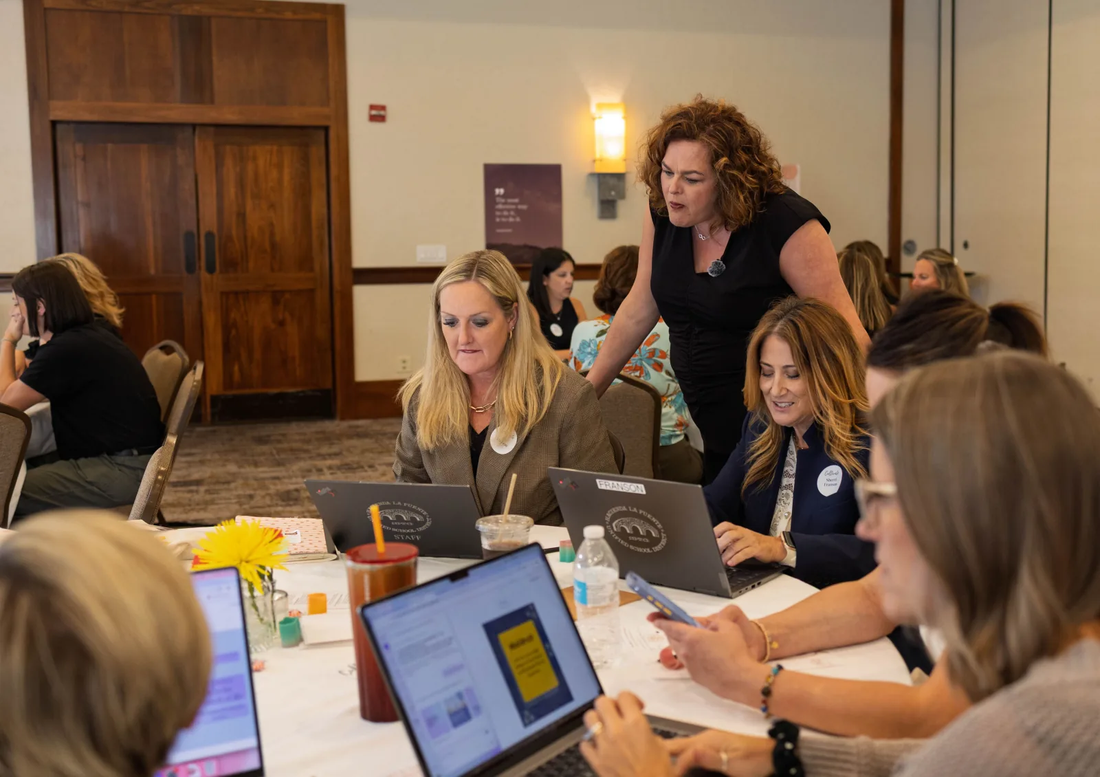 Facilitator reviews results with two leaders at their laptops after a session